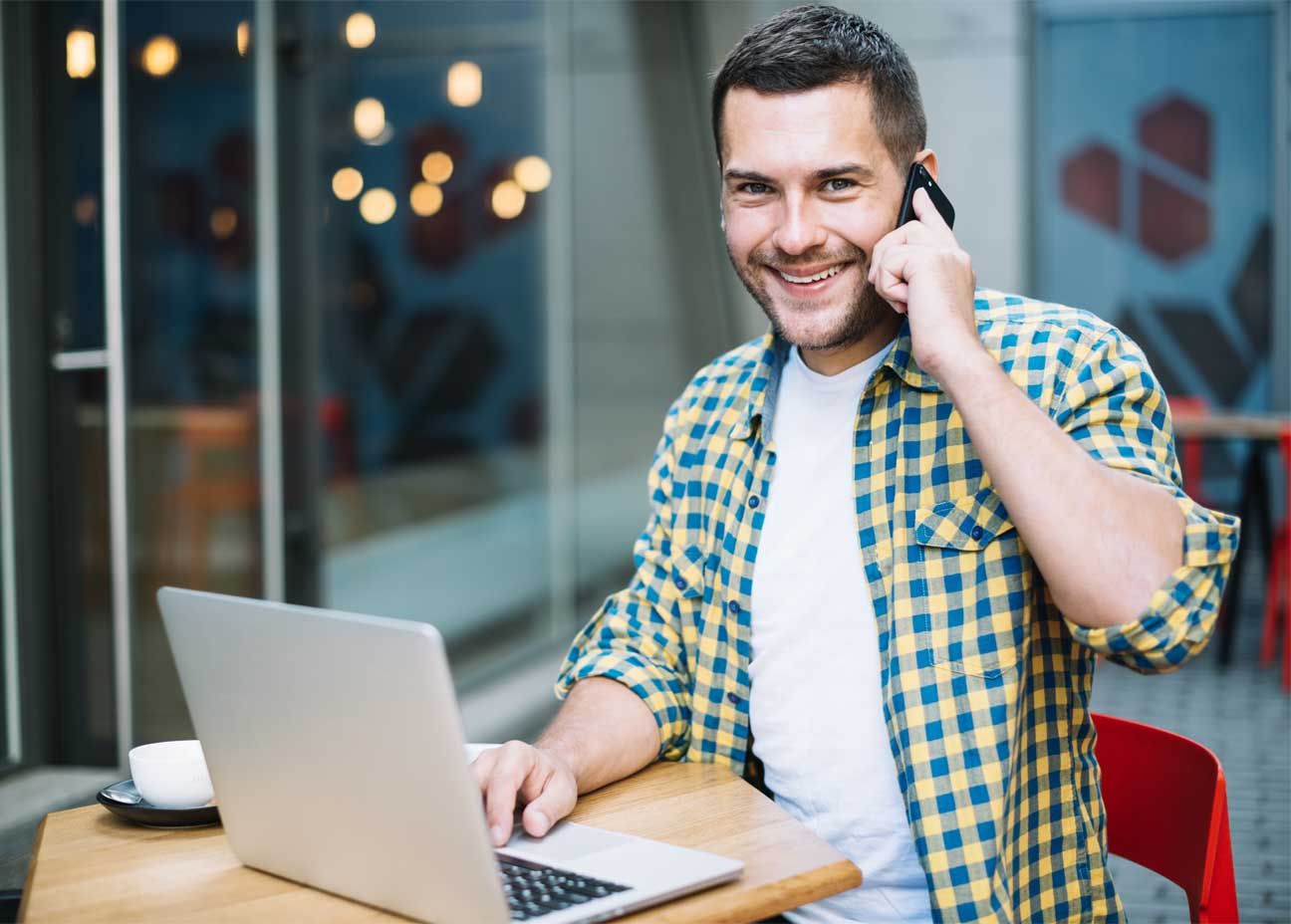 autónomo sonriendo con el portátil y un teléfono autónomo sonriendo con el portátil y un teléfono